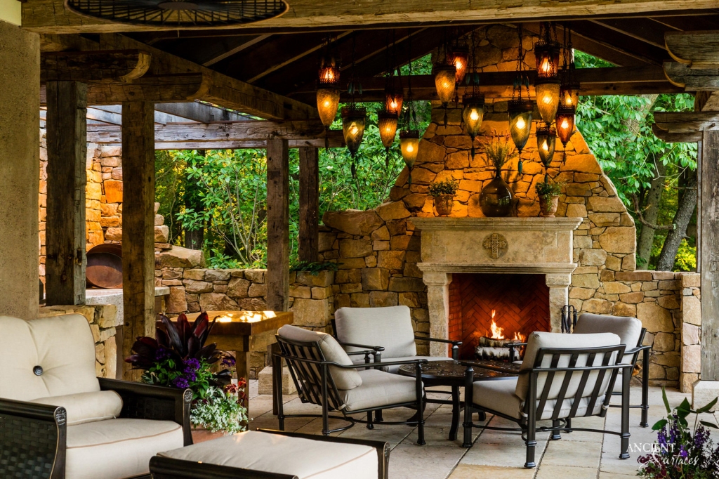 An outdoor setting at dusk, with an Ancient limestone fireplace standing tall, its facade illuminated by the soft glow of the setting sun, capturing the essence of gatherings