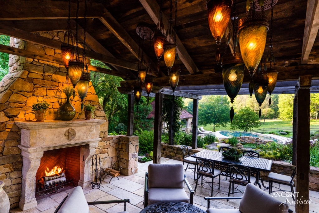 An outdoor setting at dusk, with a limestone fireplace standing tall, its facade illuminated by the soft glow of the setting sun, capturing the essence of gatherings crafted by Ancient Surfaces